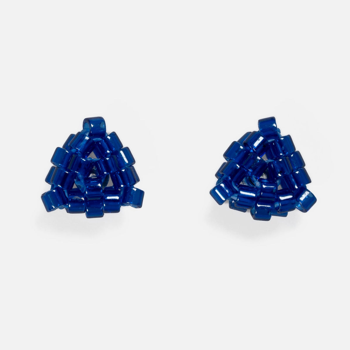 Pair of tiny triangular beaded stud earrings in glossy cobalt blue, front view on a light gray background