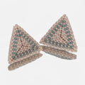 Pair of hand-woven blush, cream, and seafoam beaded triangle earrings, standing on a mirror