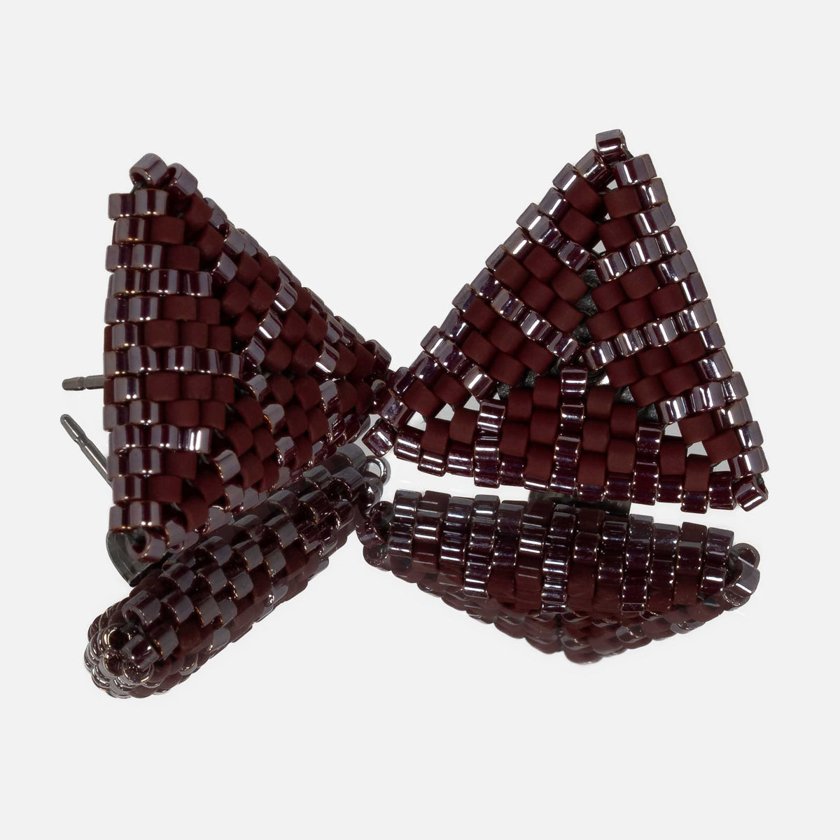 Pair of small hand-woven beaded triangle earrings in matte and glossy burgundy, standing on a mirror