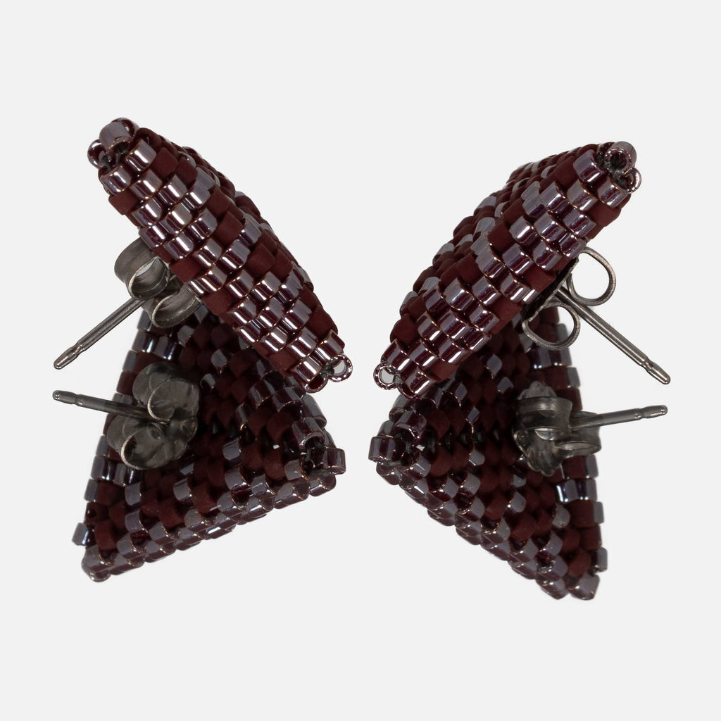 Pair of burgundy beaded triangle earrings facing each other on a mirror, showing the titanium posts and the woven edges
