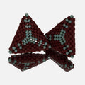 Pair of hand-woven beaded triangle earrings in matte burgundy with lines of seafoam green, standing on a mirror