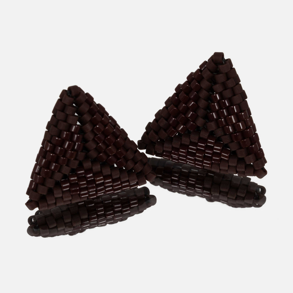 Pair of small hand-woven beaded triangle earrings in glossy and matte chocolate brown, standing on a mirror