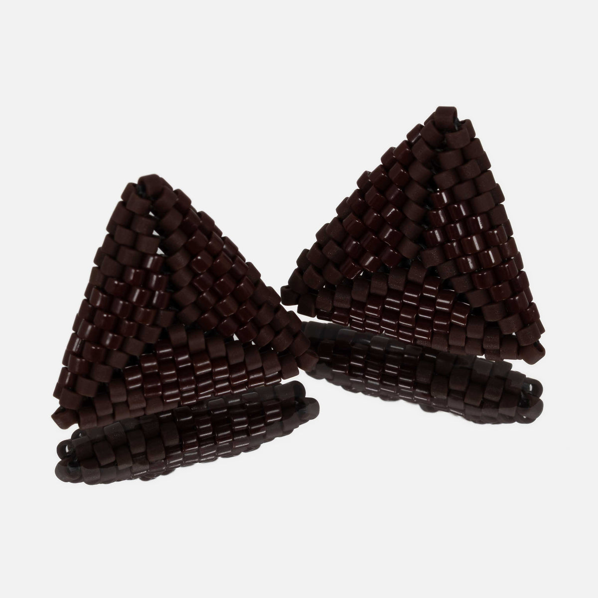 Pair of small hand-woven beaded triangle earrings in glossy and matte chocolate brown, standing on a mirror