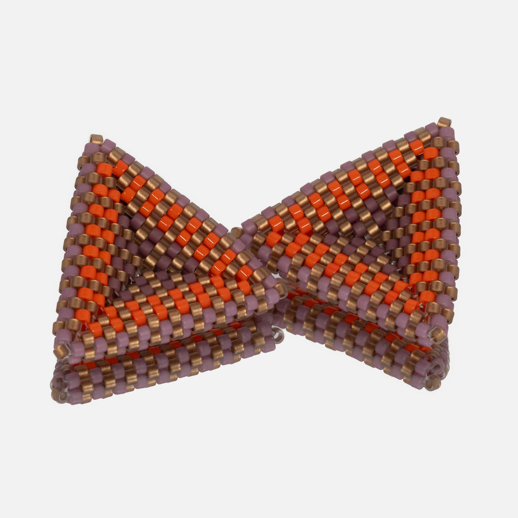 Pair of hand-woven beaded triangle earrings in pastel lilac, matte gold, and sunset orange stripes, standing on a mirror