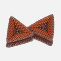 Pair of hand-woven beaded triangle earrings in pastel lilac, matte gold, and sunset orange stripes, standing on a mirror