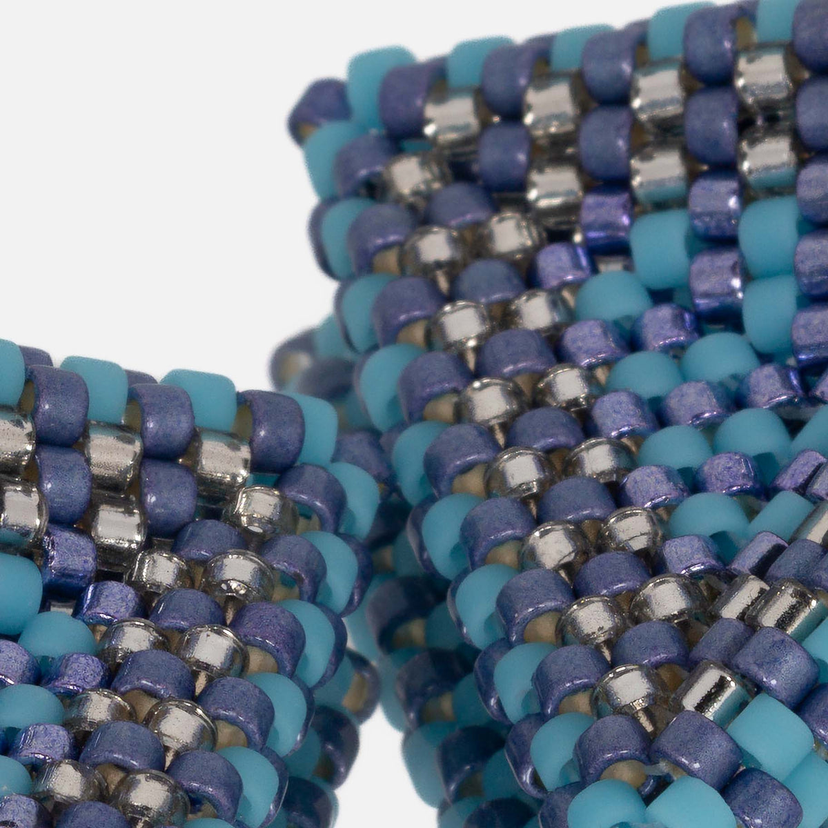 Close-up of matte and shiny metallic periwinkle, turquoise, and silver cylinder beads woven in peyote stitch