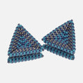 Pair of hand-woven beaded triangle earrings with periwinkle, turquoise, and silver stripes, standing on a mirror