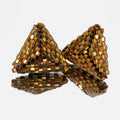 Pair of hand-woven metallic gold beaded triangle earrings, standing on a mirror