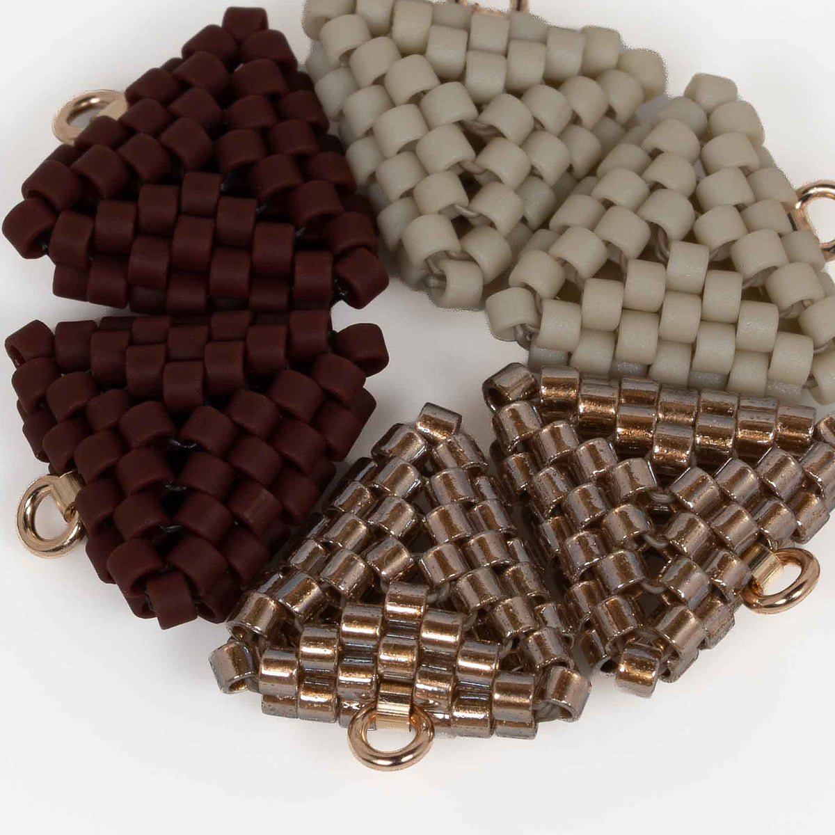 Close-up of matte greige, copper-lined, and matte oxblood cylinder beads woven in peyote stitch.