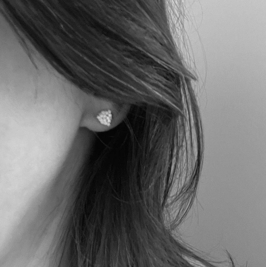 Black and white photo of a tiny beaded triangle stud worn on an earlobe, shown for size.