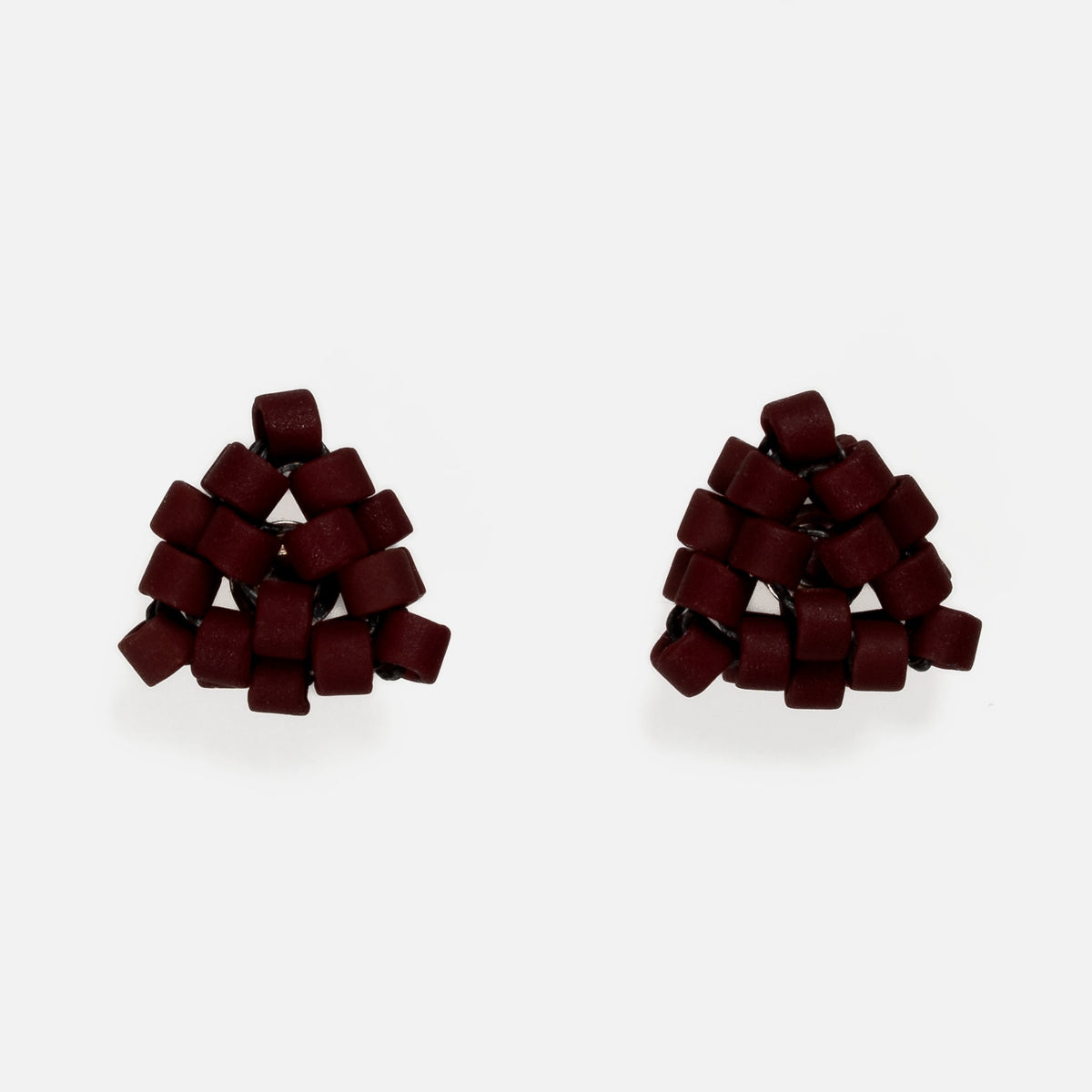 Pair of tiny triangular beaded stud earrings in matte deep burgundy red, front view on a light gray background