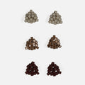 Three pairs of tiny triangular beaded stud earrings in matte greige, antique copper-lined glass, and matte oxblood, arranged in rows on a light gray background