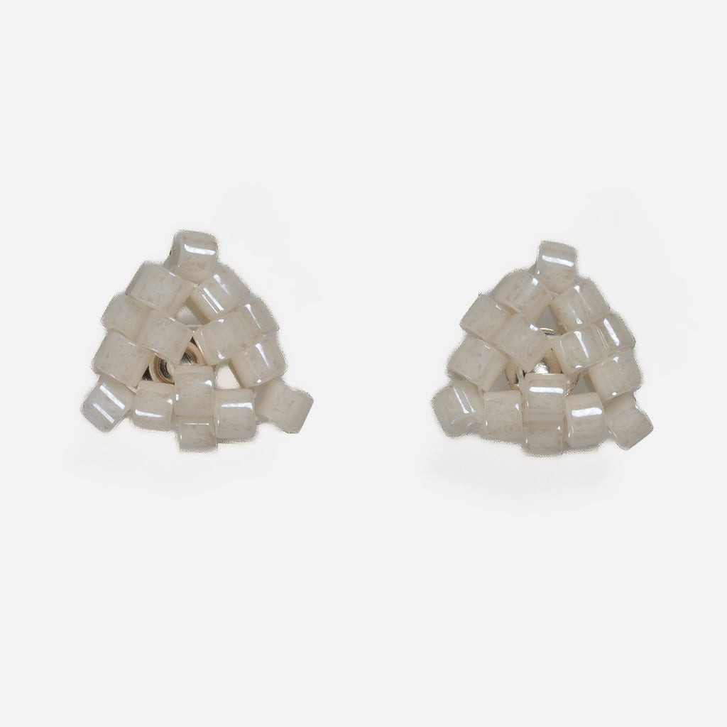 Pair of tiny triangular beaded stud earrings in warm ivory with a pearly luster, front view on a light gray background