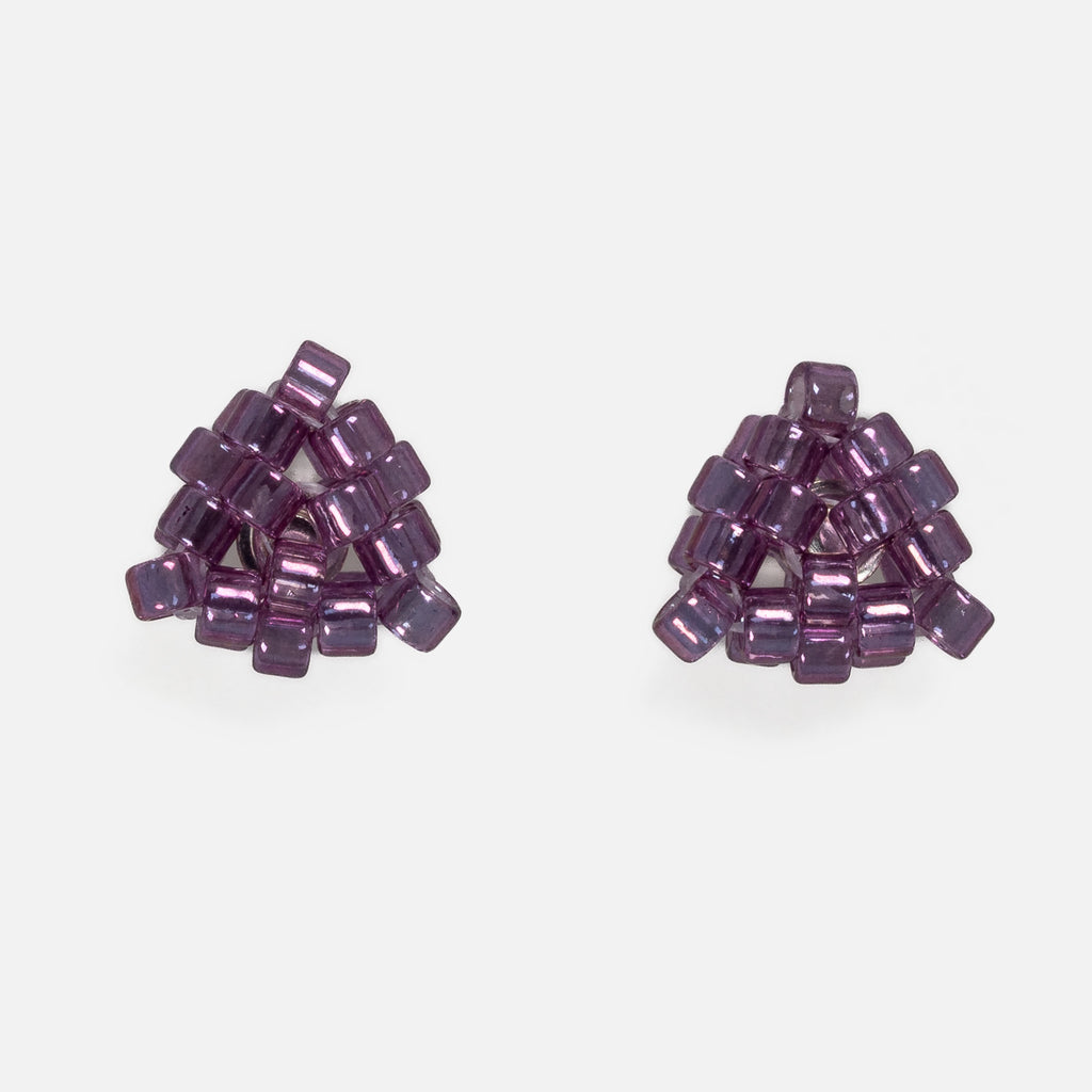 Pair of tiny triangular beaded stud earrings in glossy transparent plum purple, front view on a light gray background