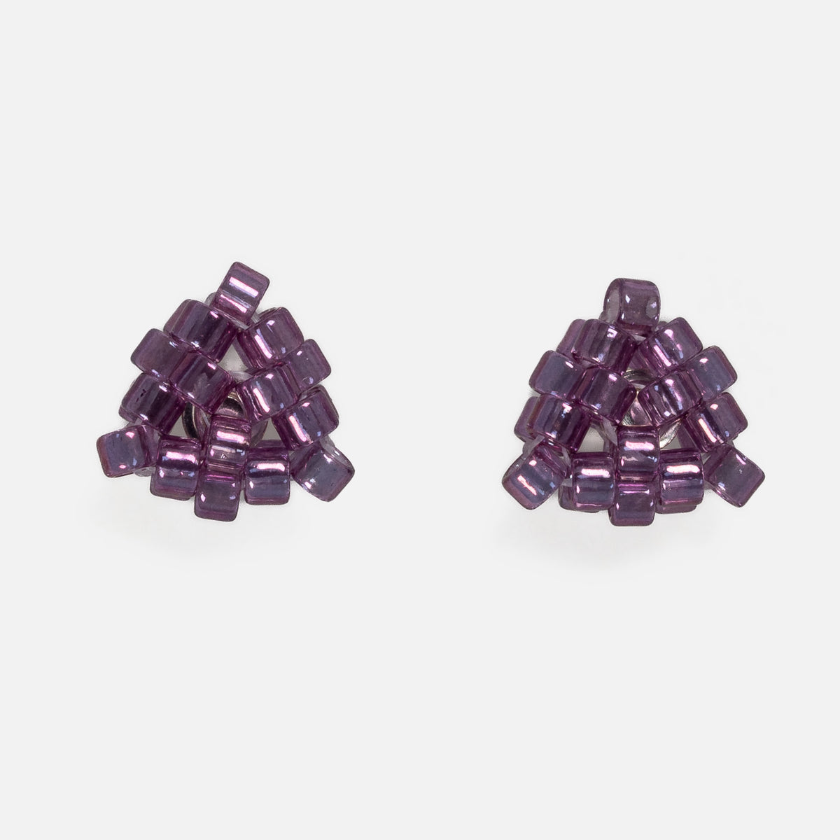Pair of tiny triangular beaded stud earrings in glossy transparent plum purple, front view on a light gray background