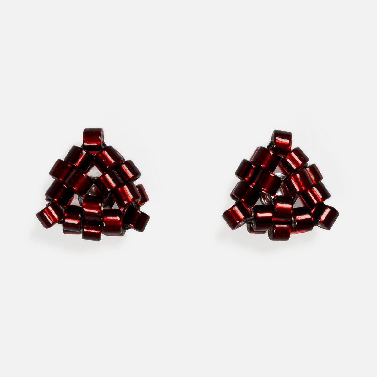 Pair of tiny triangular beaded stud earrings in silver-lined cranberry red, front view on a light gray background