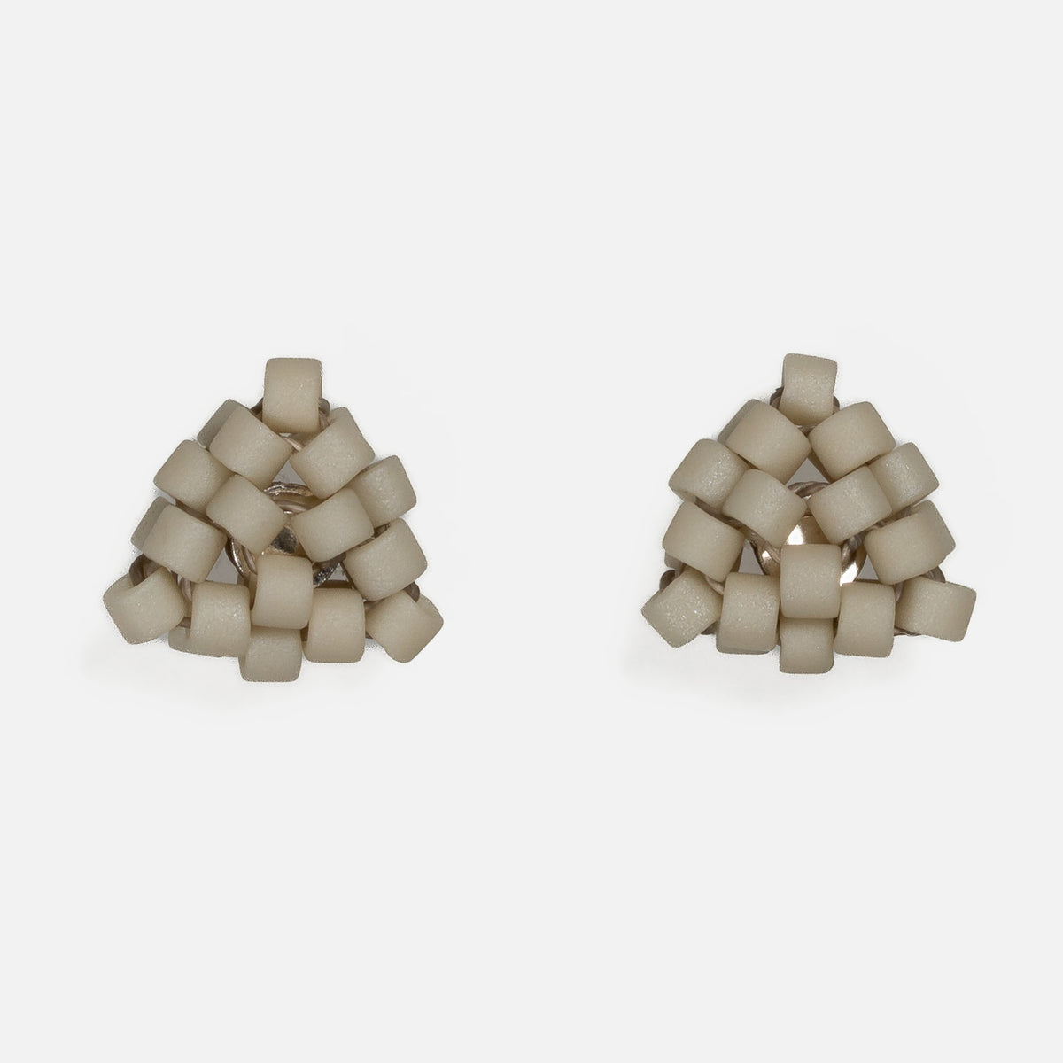 Pair of tiny triangular beaded stud earrings in matte greige, a soft warm gray-beige, front view on a light gray background