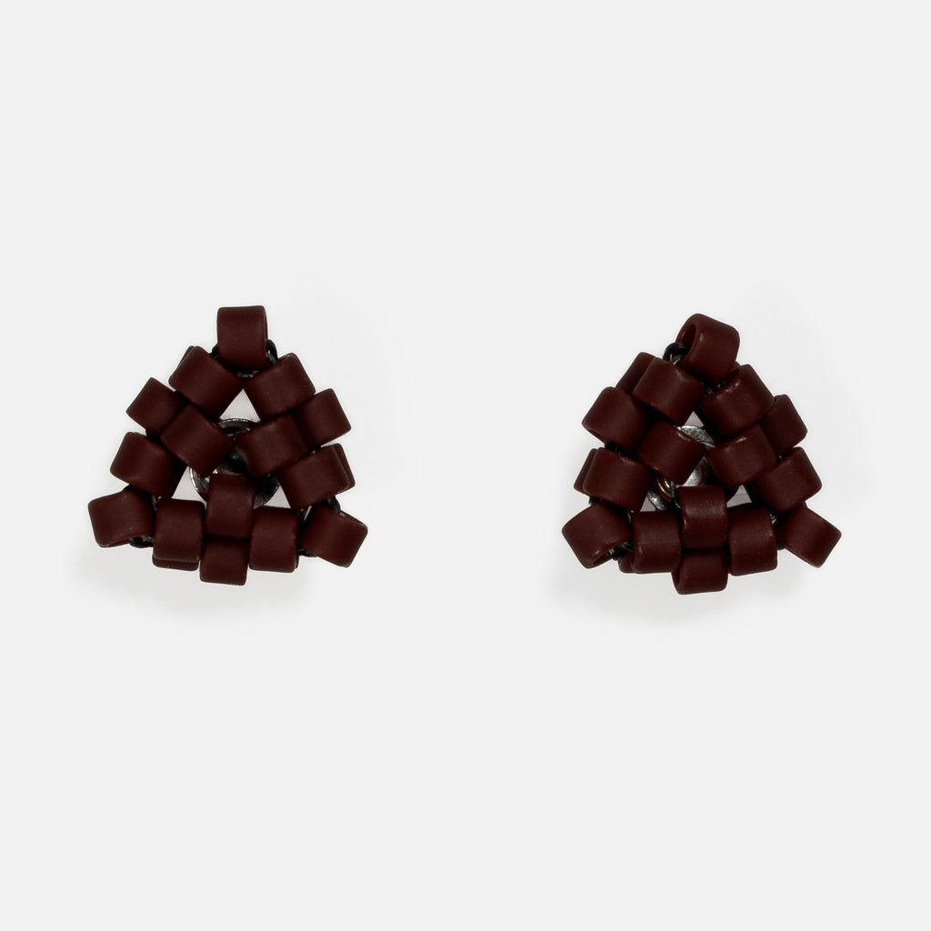 Pair of tiny triangular beaded stud earrings in matte oxblood red, front view on a light gray background