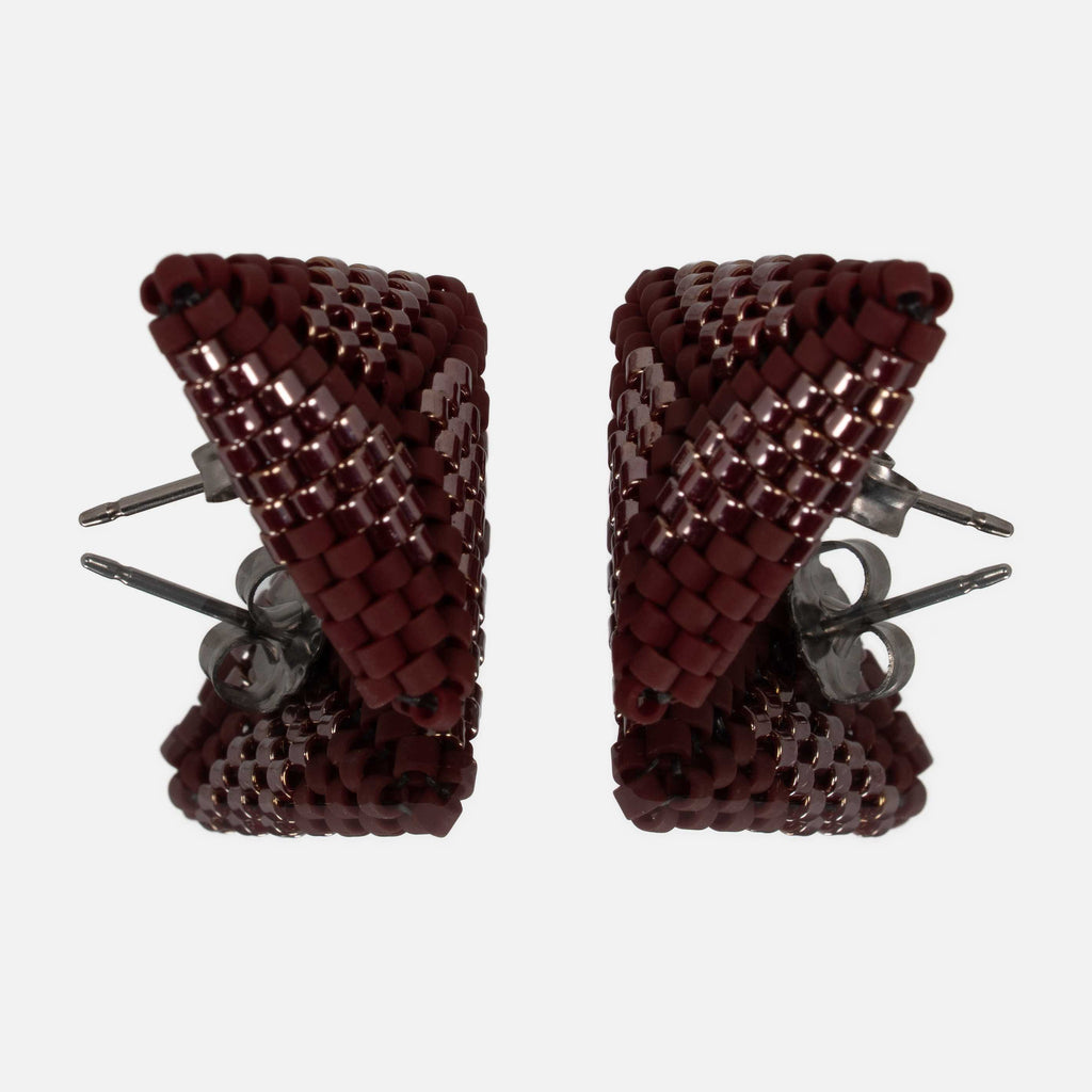 Pair of burgundy beaded triangle earrings facing each other on a mirror, showing the titanium posts and the woven edges
