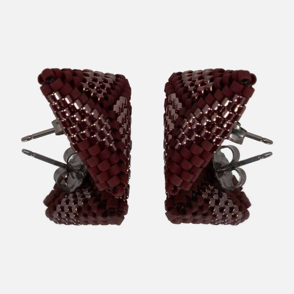 Pair of burgundy beaded triangle earrings facing each other on a mirror, showing the titanium posts and the woven edges