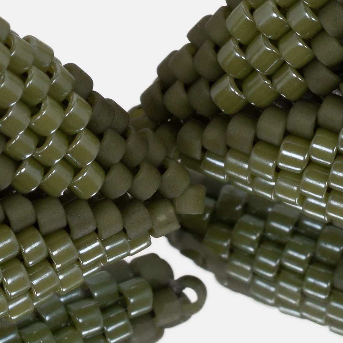 Close-up of matte olive and luster green cylinder beads woven in peyote stitch