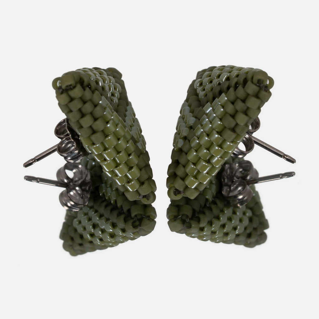Pair of olive green beaded triangle earrings facing each other on a mirror, showing the titanium posts and the woven edges