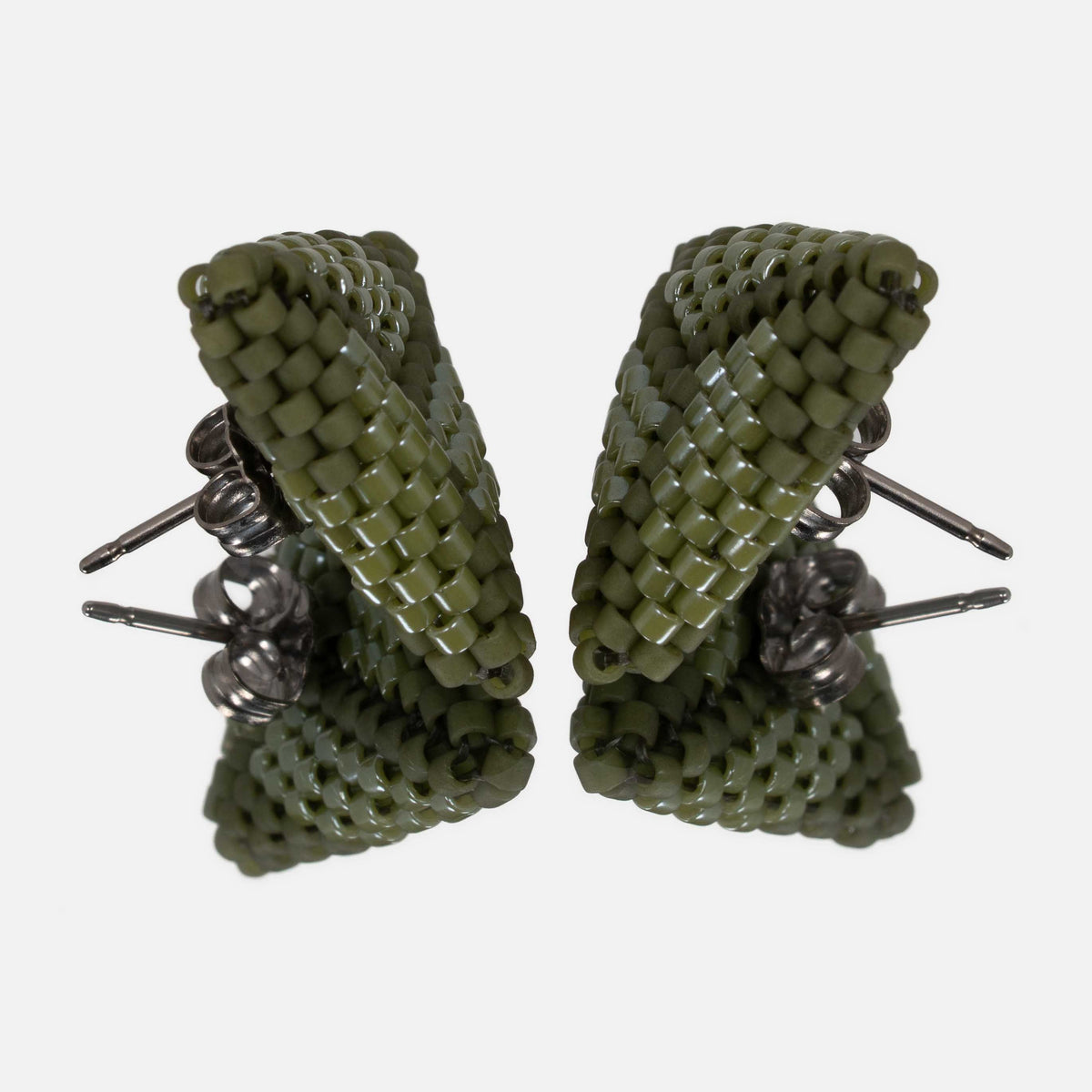 Pair of olive green beaded triangle earrings facing each other on a mirror, showing the titanium posts and the woven edges