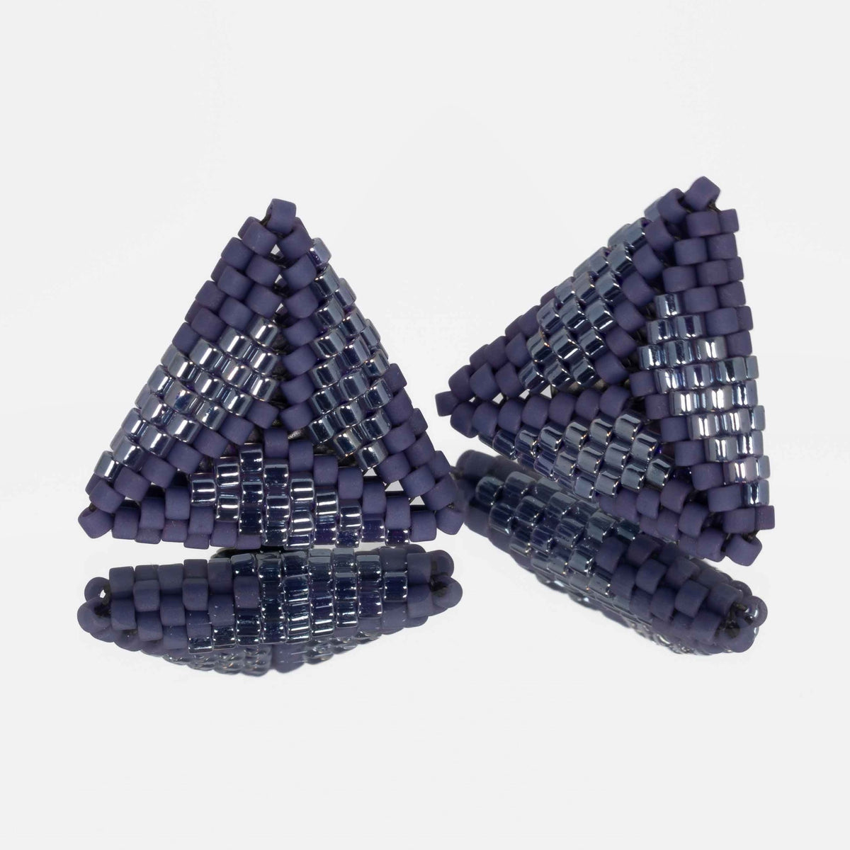 Pair of hand-woven periwinkle beaded triangle earrings, standing on a mirror