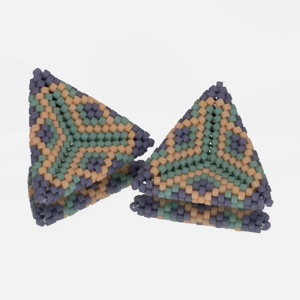 Pair of hand-woven periwinkle, sea green, and tan beaded triangle earrings, standing on a mirror