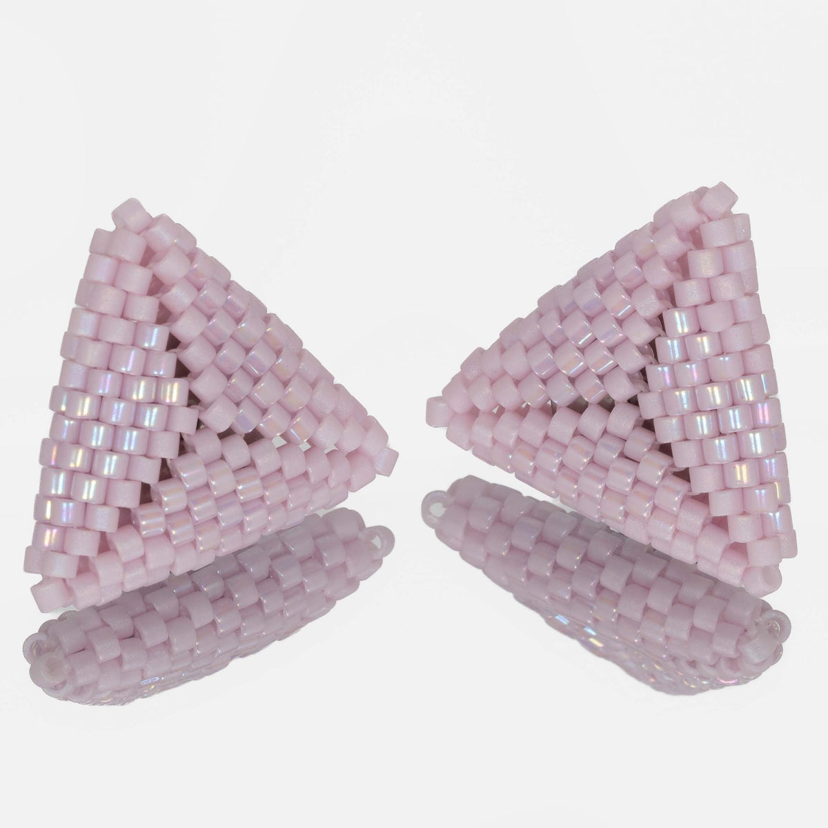 Pair of hand-woven pink lilac beaded triangle earrings, standing on a mirror
