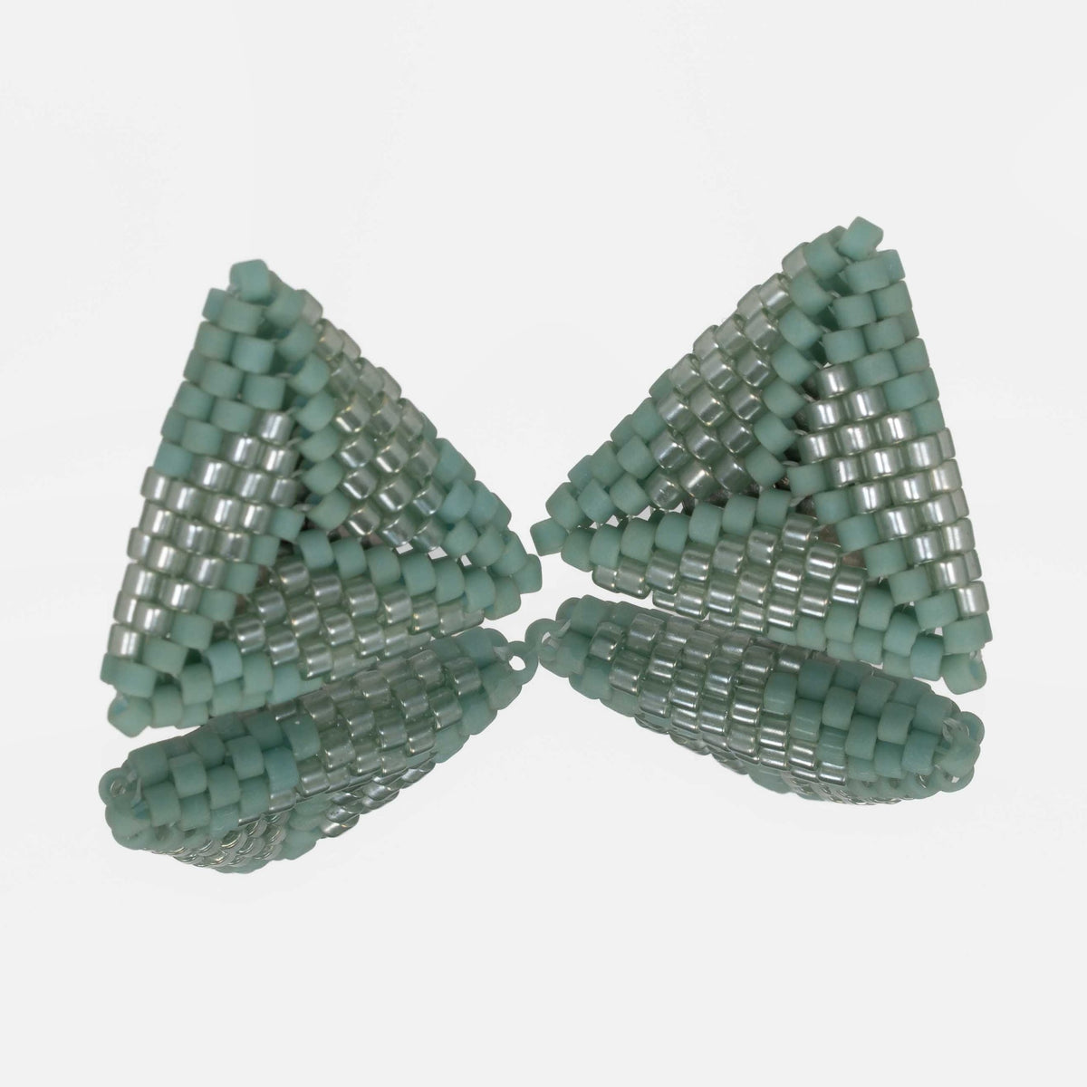 Pair of hand-woven sea green beaded triangle earrings, standing on a mirror